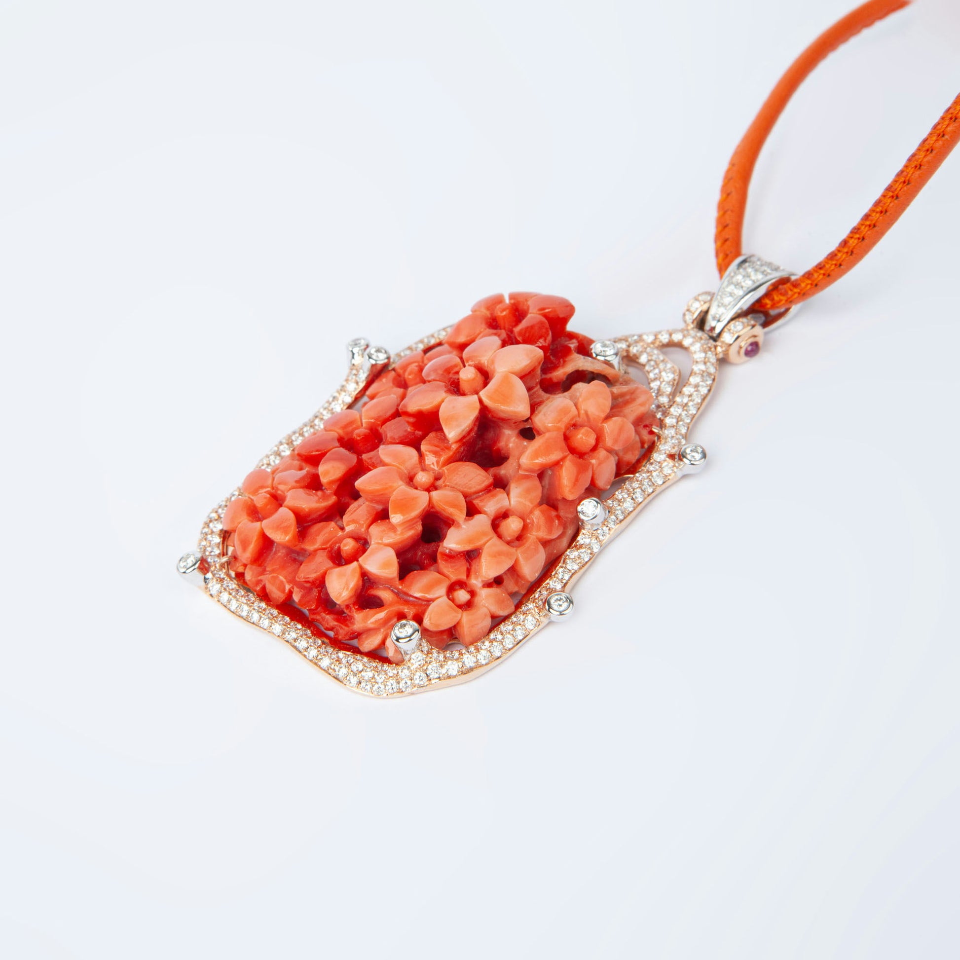 Pendant in gold featuring natural coral 81.82 ct and 231 natural diamonds 1.85 ct with ruby accent 0.12 ct.